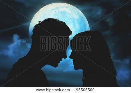 Silhouettes of a young couple under the moonlit sky.
