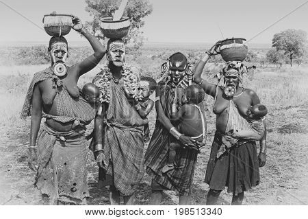 JINKA, ETHIOPIA - NOVEMBER 21, 2014: Mursi women with traditional lip plate and children on November 21, 2014 in Jinka, Ethiopia.