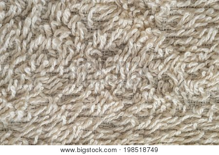 Macro shot of a beige color towel. Texture is similar to the texture of a fleecy knotted-pile carpet. Chaotic pattern of villi on fabric material.