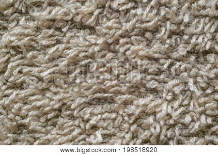Macro shot of a beige color towel. Texture is similar to the texture of a fleecy knotted-pile carpet. Chaotic pattern of villi on fabric material.
