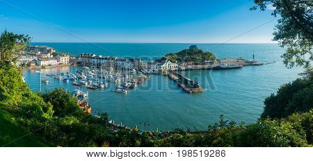 Ilfracombe Harbor at sunrise in broad panorama across the picturesque town.
