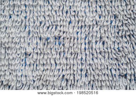 Macro shot of a white towel. Texture is similar to the texture of a fleecy knotted-pile carpet. Geometric pattern of villi on fabric material. White villi on a blue base