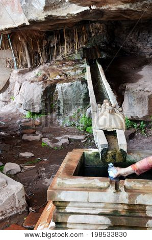 Traveler People Fill Holy Or Blessed Water Flow From Stone Mountain Into Plastic Bottle At Ruins Of