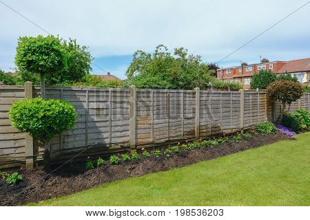 Flower bed with garden fence and lawn taken in early summer.