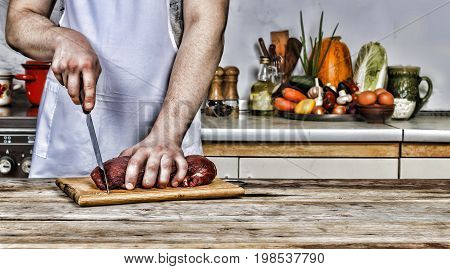 Man in the kitchen cutting a piece of meat beef