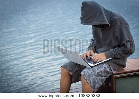 A Young Man Wearing A Hooded Sweatshirt Sitting Near The Old Television.a Hacker With A Laptop.