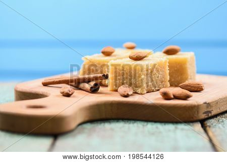 Indian traditional dessert halva wih cinnamon and almonds served on wooden board on blue background copyspace closeup