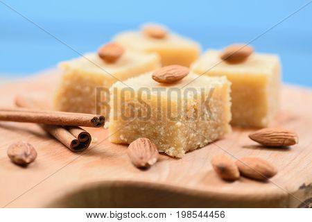 Indian traditional dessert halva made with semolina and milk wih cinnamon and almonds on blue background close up closeup