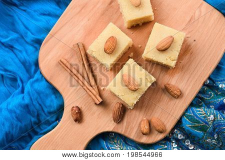 Homemade Indian sweets halva wih cinnamon and almonds served on embroidered blue cloth top view overhead view