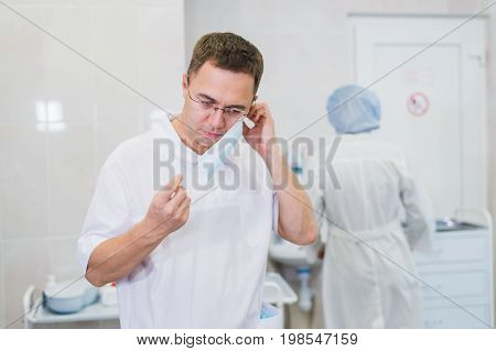 Thoughtful male surgeon wearing surgical mask in hospital.