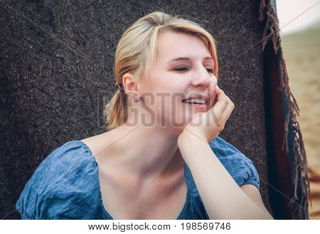 Blond caucasian girl with her head resting on her hand, photograph taken in beduin camp in desert camp in Merzouga, Morocco