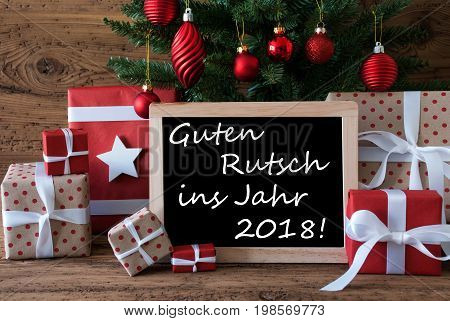 Colorful Card For Seasons Greetings. Christmas Tree With Red Balls. Gifts Or Presents In The Front Of Wooden Background. Chalkboard With German Text Guten Rutsch Ins Jahr 2018 Means Happy New Year