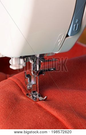 Close up of sewing machine working with red fabric