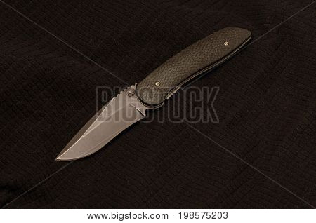 Black Knife On A Black Background. Front View. Black On Black.