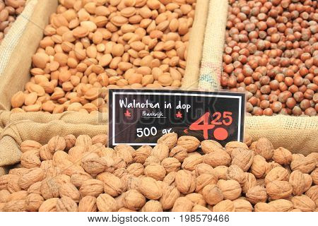 Fresh unpealed nuts on a market stall (text on tags: names and prices of various nuts in Dutch walnuts Pecan almonds and hazel)