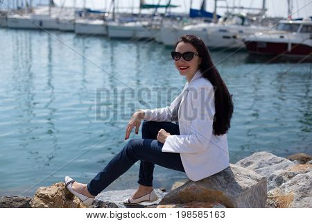 Woman Dressed In Nautical Style Sitting By Seaside In Yacht Mari
