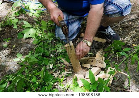 Man splitting log on chopping block with axe