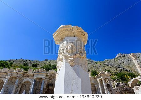 Carved marble column in agora of ancient city of Sagalassos with agora on background