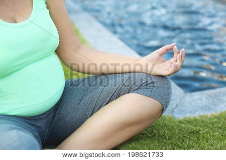 Beautiful pregnant woman meditaiting in summer park. Pregnant yoga