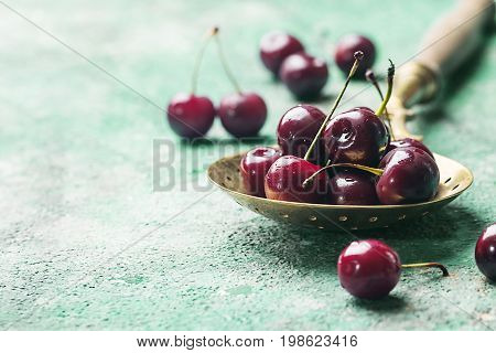 Fresh cherry in spoon over blue background. ripe cherries. sweet berries.