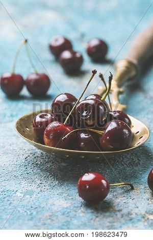 Fresh cherry in spoon over blue background. ripe cherries. sweet berries.