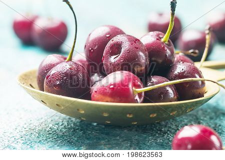 Fresh cherry in spoon over blue background. ripe cherries. sweet berries.