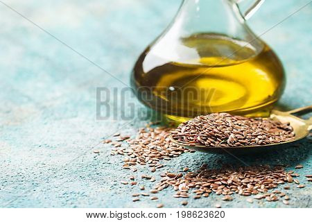 flax seeds and linseed oil in a glass jug over blue background, healthy diet with omega 3 fatty acids