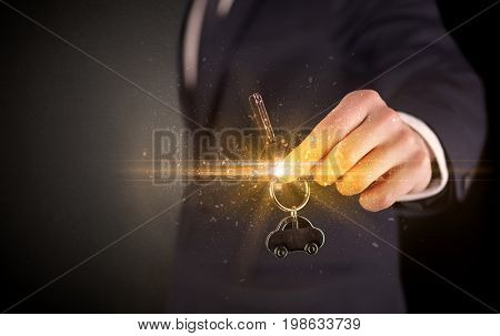 Businessman hand  over shiny keys in dark suit with dark background