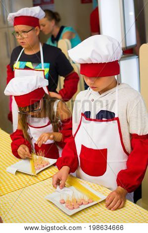 Alchevsk, Ukraine - July 30, 2017: School Cooks For Children. Learn To Cook Pasta With Sausages