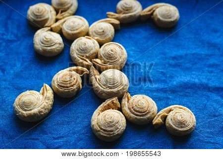 view from above of fresh baked homemade sweet puff pastry bagel roll as spiral with sugar and cinnamon on blue jeans cloth background