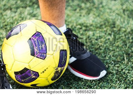 Feet Of Man In Sneakers And Soccer Ball On A Field