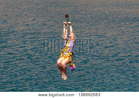 Ukraine Migea - July 30 2017: Zipline. The woman in the equipment slides on a steel cable. Trolley Track Over the lake. Extreme and active rest.