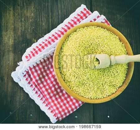 Millet cereal in a wooden plate on a red napkin topr view
