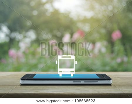Bus flat icon on modern smart phone screen on wooden table over blur pink flower and tree Business transportation service concept