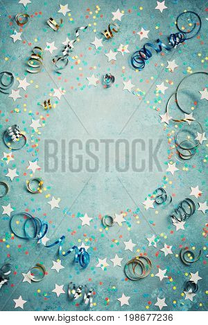 Party carnival or birthday frame with colorful confetti and streamer on vintage blue table top view. Flat lay style. Holiday mockup. Greeting card with copy space.