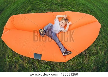 Cute Boy Resting On An Air Sofa In The Park.