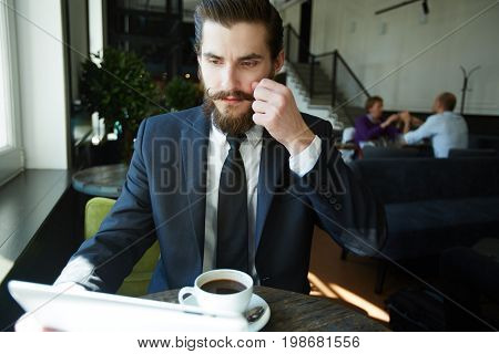 Contemporary salesman looking through online data in tablet