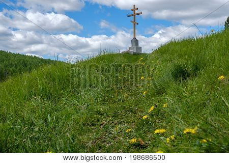 the cross on the mountain, the grass is green and the path leading to the cross