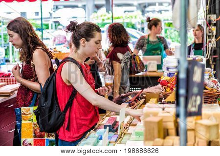 Montreal Canada - May 28 2017: Woman buying soap bars in Jean Talon market with people inside building in city in Quebec region