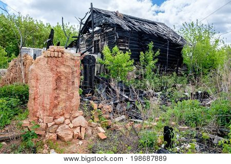 wooden house after a fire on a background of green trees in the village