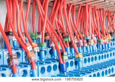 Many intermediate relays installed in a row. They are connected with many wires red with marking. Wires connected to the relay via cable lugs. Markings of different colors with numbers.