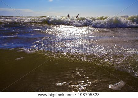 Swimmers enjoy the storm sea waves.sun set