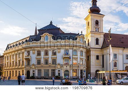 SIBIU ROMANIA - JUNE 19 2017: Large main square Huet with City Hall Catholic Church tourists on the street ancient medieval city.