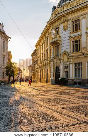 SIBIU ROMANIA - JUNE 19 2017: Large main square Huet with City Hall and people on the street at golden sun light ancient medieval city.