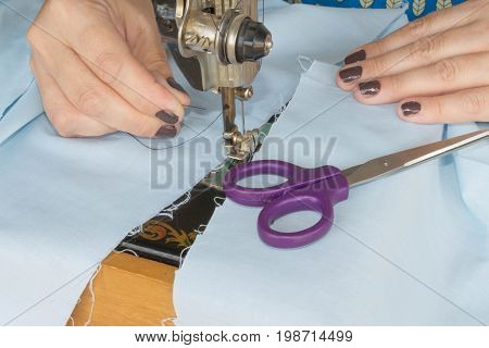 closeup of woman hands sewing yellow cloth outdoors. Woman's Hand Sewing Quilt