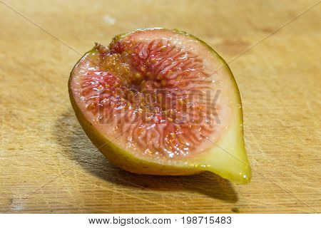 Horizontal photo of a close up on a half of a cut fig on a wooden cutting board