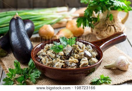 Stewed aubergines in a bowl on a wooden background