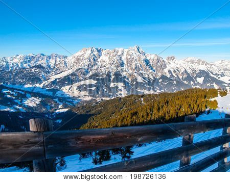 High rocky snowy peak on sunny winter day with blue sky. Alpine mountain ridge.