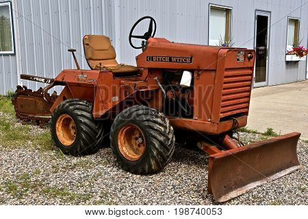 ALEXANDRIA, MINNESOTA, August 5, 2017: The tractor trencher is a Ditch Witch, a trade name of Charles Machine Works, an American brand of underground utility construction equipment, which has been in operation since 1949 from Perry, Oklahoma.