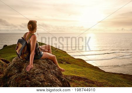 traveller with backpack enjoying sunset listening to music on peak of mountain. Mountains and sea landscape travel to Asia happiness emotion summer holiday concept
